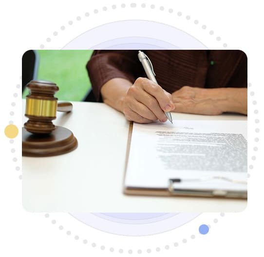 A person is writing on paper next to a judge 's gavel.