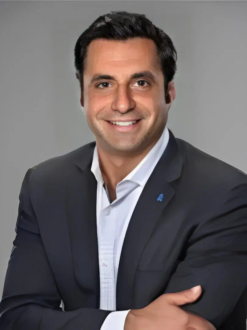 A man in a suit and tie smiling for the camera.